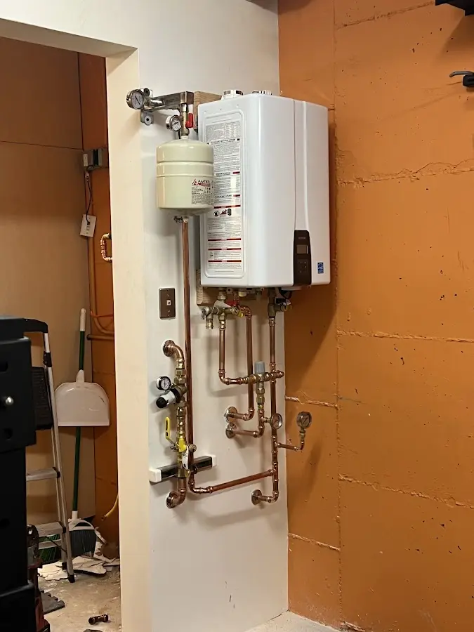 Plumbing technician inspecting water heater connections in Sturtevant